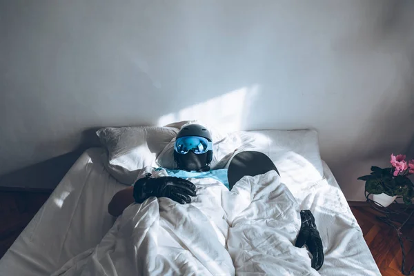 Homem na cama com snowboard óculos de esqui e capacete — Fotografia de Stock