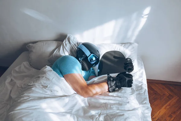 Человек в постели со сноубордом лыжные гуглы и шлем — стоковое фото