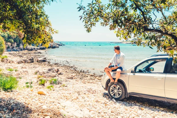 夏天的海滩上，一个拿着咖啡杯站在汽车旁边的男人 — 图库照片
