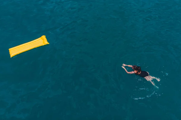 Молодая женщина плавает в голубой лазурной воде — стоковое фото