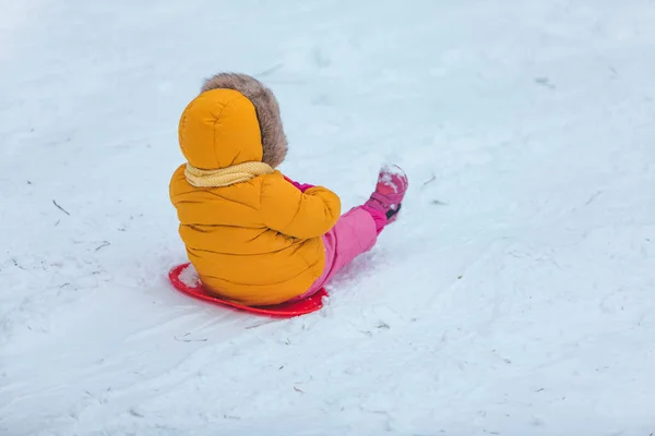 Klein kind op slee glijden door de winter heuvel — Stockfoto
