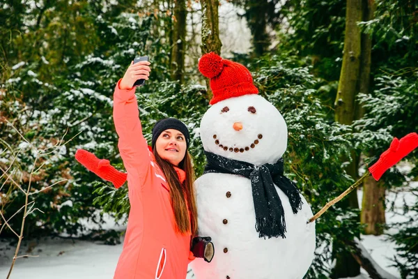 Mooie vrouw het nemen van selfie met sneeuwpop — Stockfoto