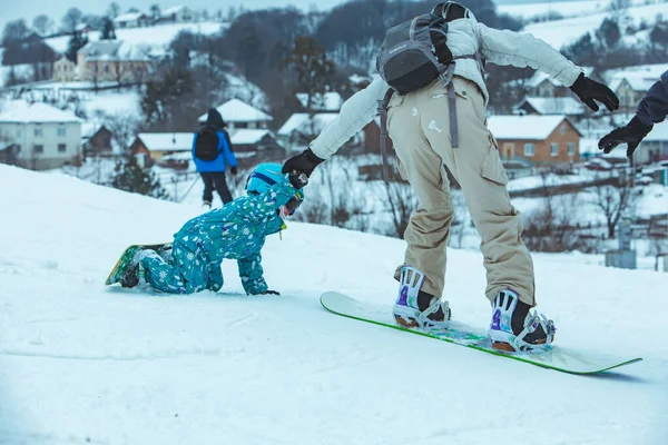 Madre enseñando a niña a hacer snowboard —  Fotos de Stock