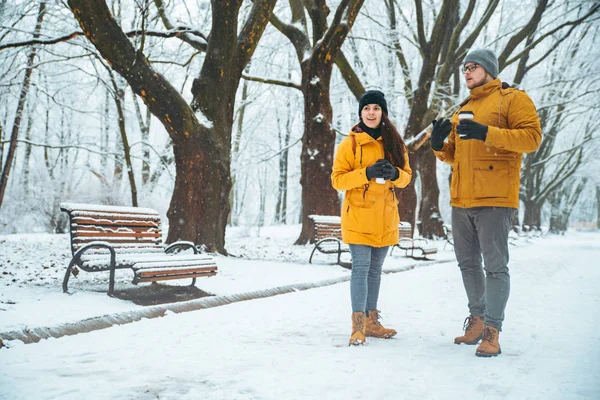 Casal andando pelo parque da cidade nevada falando socialização. data romântica no tempo de inverno — Fotografia de Stock