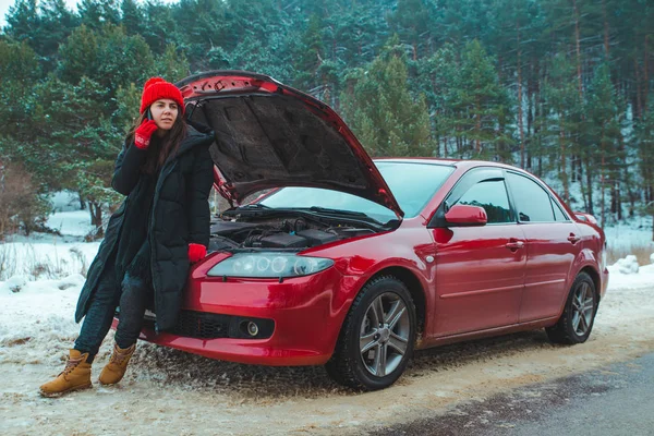 Женщина зовет на помощь со сломанной машиной на зимнем шоссе — стоковое фото
