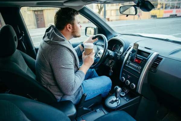 Rozzlobený muž řídí auto a pije kávu. zhroucení provozu — Stock fotografie