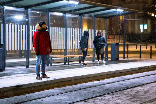 Человек зимой заснеженной ночью на железнодорожном вокзале ждет трамвай — стоковое фото