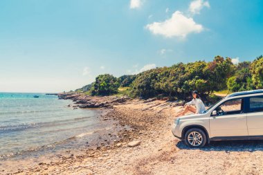 yaz plaj tatil konseptinde oto kaput üzerinde oturan kadın