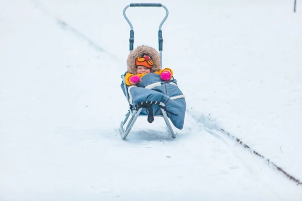 Liten unge på släde glider ner på vintern kulle — Stockfoto