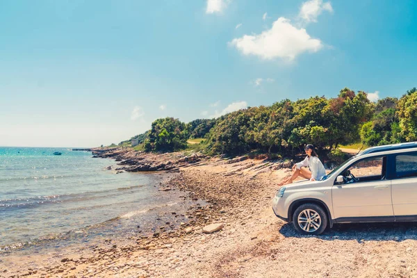 Frau sitzt bei Sommerurlaub am Strand auf Motorhaube — Stockfoto