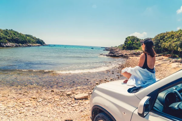 Vrouw het leggen van de auto kap met uitzicht op zee zomer strand — Stockfoto