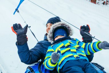 father with son on snow tube. pull up to hill