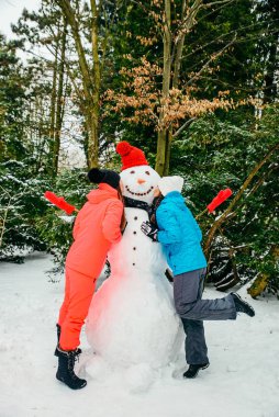 Kardan adamın yanında poz veren iki kadın.