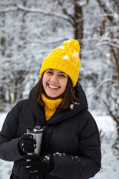 Smiling woman in winter outfit drinking warm up drink from refillable mug — 스톡 사진