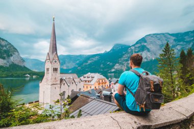 Sırt çantalı bir adam oturuyor ve Hallstatt Avusturya 'nın hayatıyla eğleniyor.