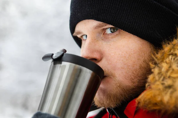 Молодой взрослый мужчина пьет кофе из многоразовых кружку на открытом воздухе — стоковое фото