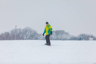 Tepenin aşağısında snowboard yapan bir adam