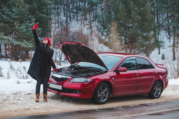 Mujer pidiendo ayuda con el coche averiado en la carretera de invierno —  Fotos de Stock