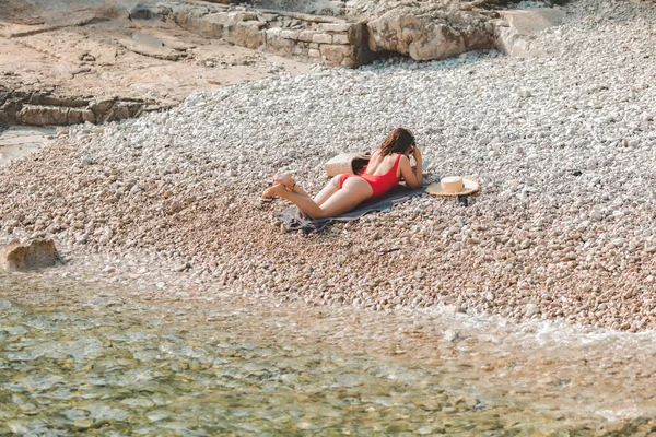 Mladý docela sexy žena ležící na skalnaté pláži opalování — Stock fotografie