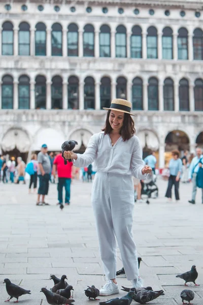 Kvinna i vita kläder med halmhatt ha kul med duvor på venice city square — Stockfoto