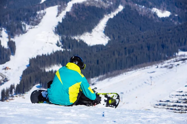 Ember ül a snowboard a hegy tetején, gyönyörű kilátással — Stock Fotó