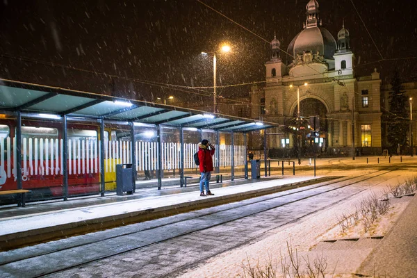 Man in red winter coat standing at bus tram stop waiting for public transport — 스톡 사진