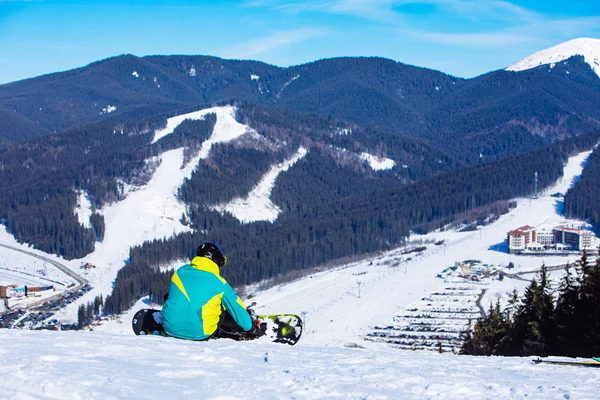Ember ül a snowboard a hegy tetején, gyönyörű kilátással — Stock Fotó