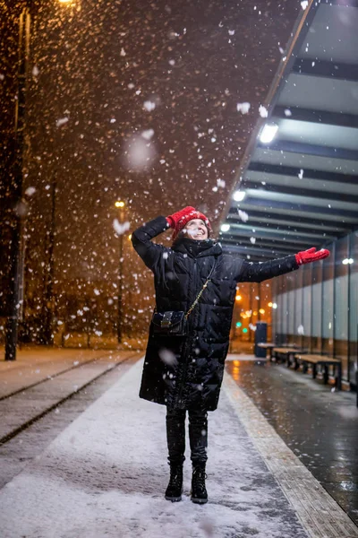 Mujer mirando la nieve de pie en la estación de tranvía noche de invierno — Foto de Stock