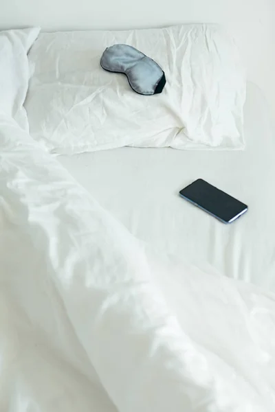 Sleeping mask with phone at bed with white sheets sunny morning — Stock Photo, Image