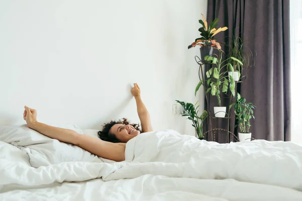 Молодая красивая женщина в постели с белыми простынями яркий свет — стоковое фото