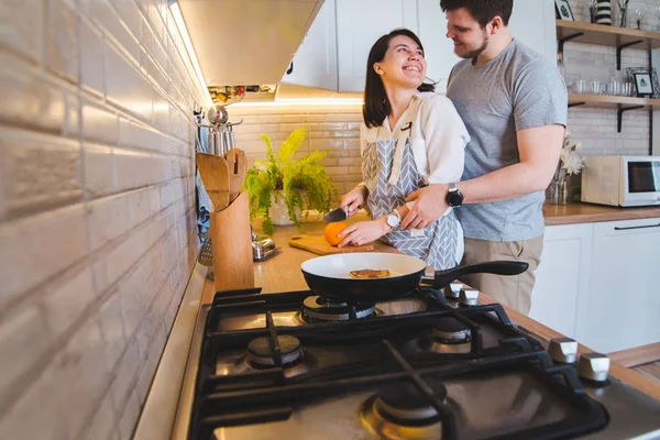 Encantadora pareja abrazándose en la cocina mientras se cocina el desayuno — Foto de Stock