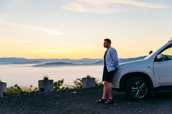 Muž, který se dívá na východ slunce v horách SUV vůz — Stock fotografie
