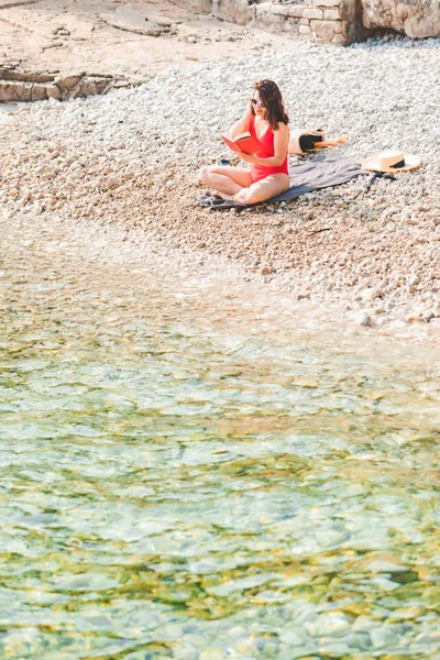 Donna che legge il libro alla spiaggia del mare — Foto Stock