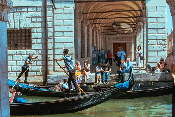 Venice, Italy - May 25, 2019: people resting at city quay looking at gondolas — Stock Photo, Image