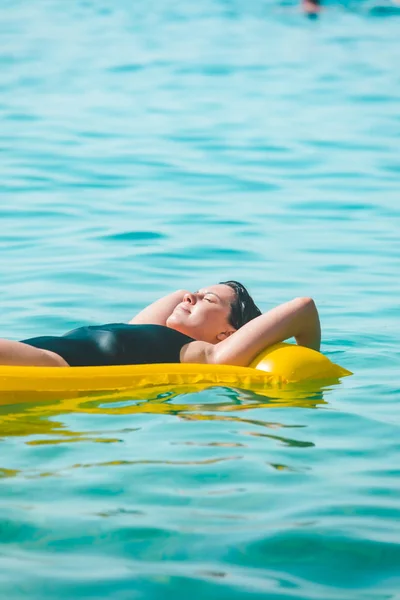 Krásná sexy žena ležící na žluté nafukovací matrace u mořské vody — Stock fotografie