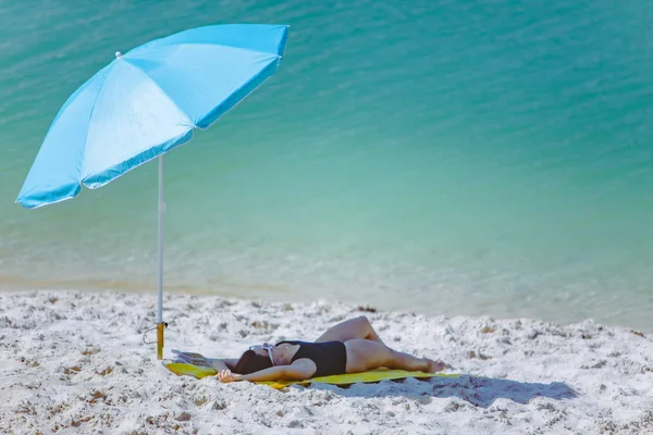 Frau im Badeanzug spazieren am Sandstrand Blauer Sonnenschirm und gelbe Decke — Stockfoto