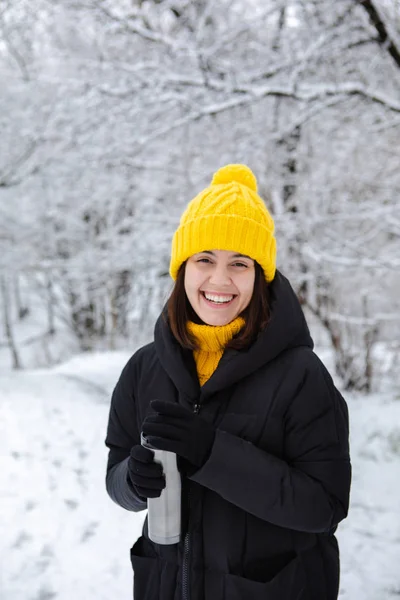 Lächelnde Frau im Winteroutfit trinkt Aufwärmgetränk aus Mehrwegbecher — Stockfoto