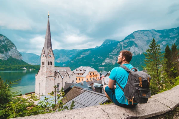 Mężczyzna z plecakiem siedzi i cieszy się z rywalizacji hallstatt austria — Zdjęcie stockowe