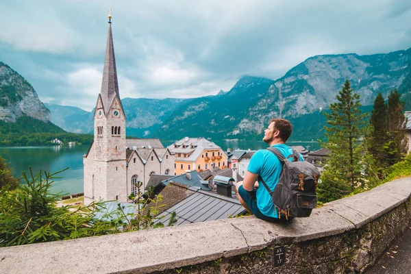 Mężczyzna z plecakiem siedzi i cieszy się z rywalizacji hallstatt austria — Zdjęcie stockowe
