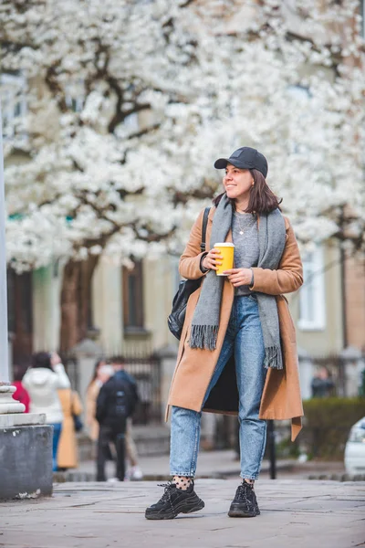 Jonge stijlvolle vrouw lopen door straat met koffiekop — Stockfoto