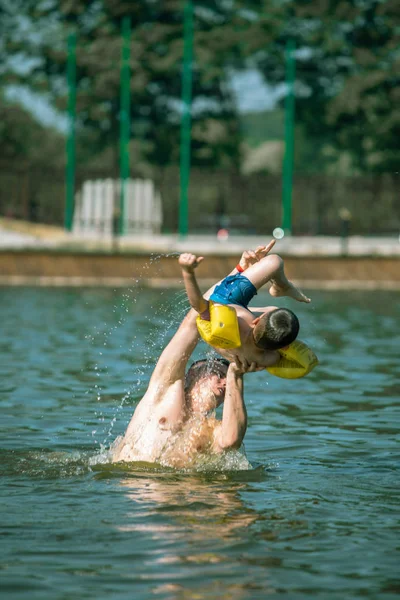 Father throwing son in water having fun — Stock Photo, Image