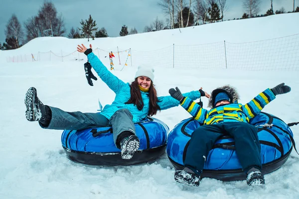 Jonge vrouw met kleine jongen op sneeuw buizen — Stockfoto