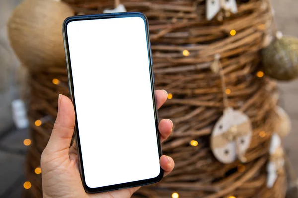 Femme main tenant le téléphone avec écran blanc arbre de Noël sur fond — Photo