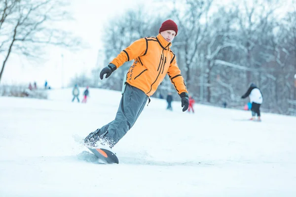Jovem homem montando snowboard por inverno colina — Fotografia de Stock