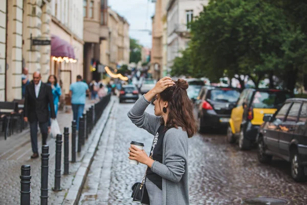 Young pretty woman at city street drinking coffee from disposable cup — ストック写真