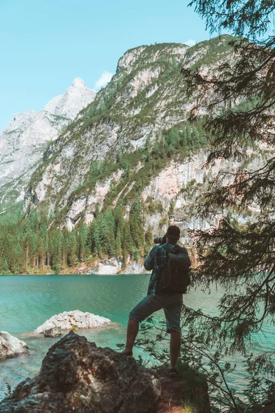 Hombre escalando por rocas para disparar hermoso paisaje de lago y montañas — Foto de Stock