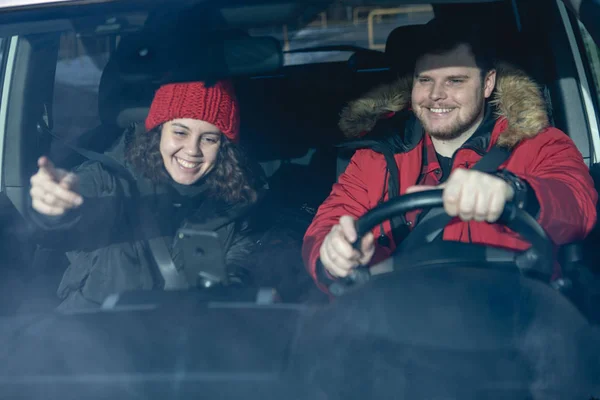 Пара в машине в зимнем наряде вождения и говорить навигации по телефону — стоковое фото