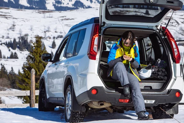Γυναίκα κάθεται σε SUV αυτοκίνητο πορτ-μπαγκάζ γεμάτο σκι και snowboard πράγματα — Φωτογραφία Αρχείου