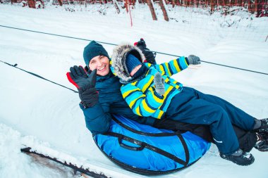 father with son on snow tube. pull up to hill