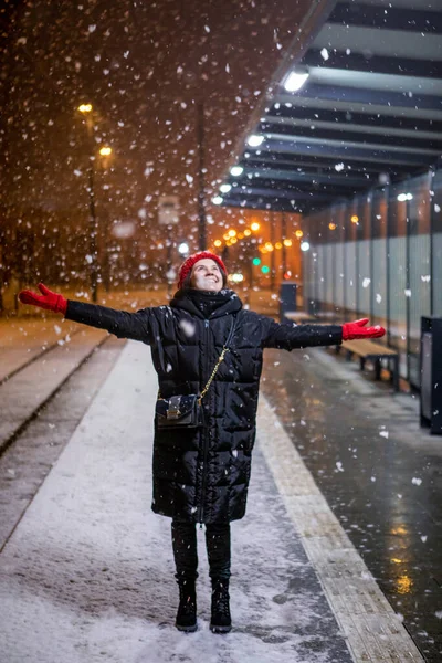 Mujer mirando la nieve de pie en la estación de tranvía noche de invierno — Foto de Stock